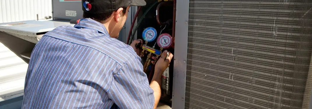 HVAC technician servicing a condenser unit in Summerfield